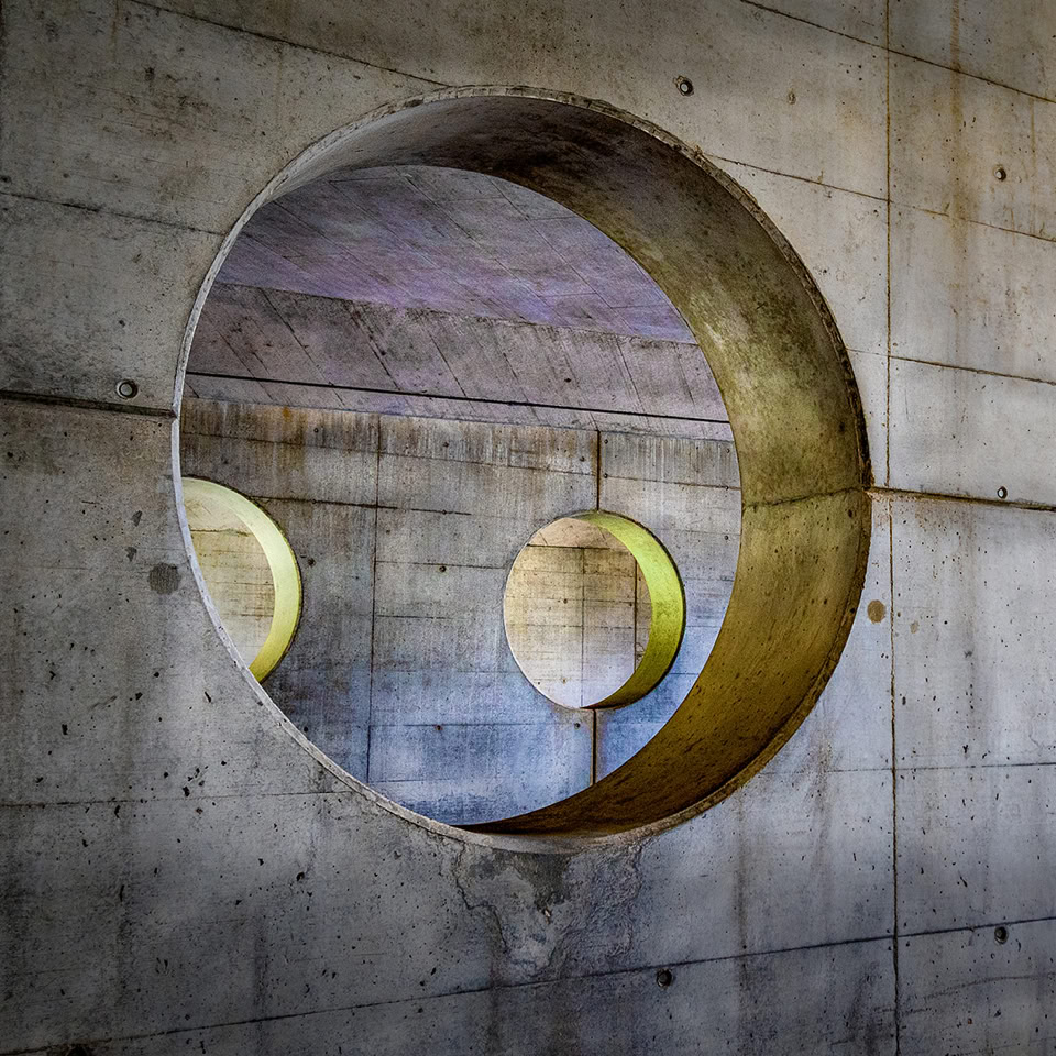 Concrete wall with two large circular openings, each containing smaller circular cutouts.