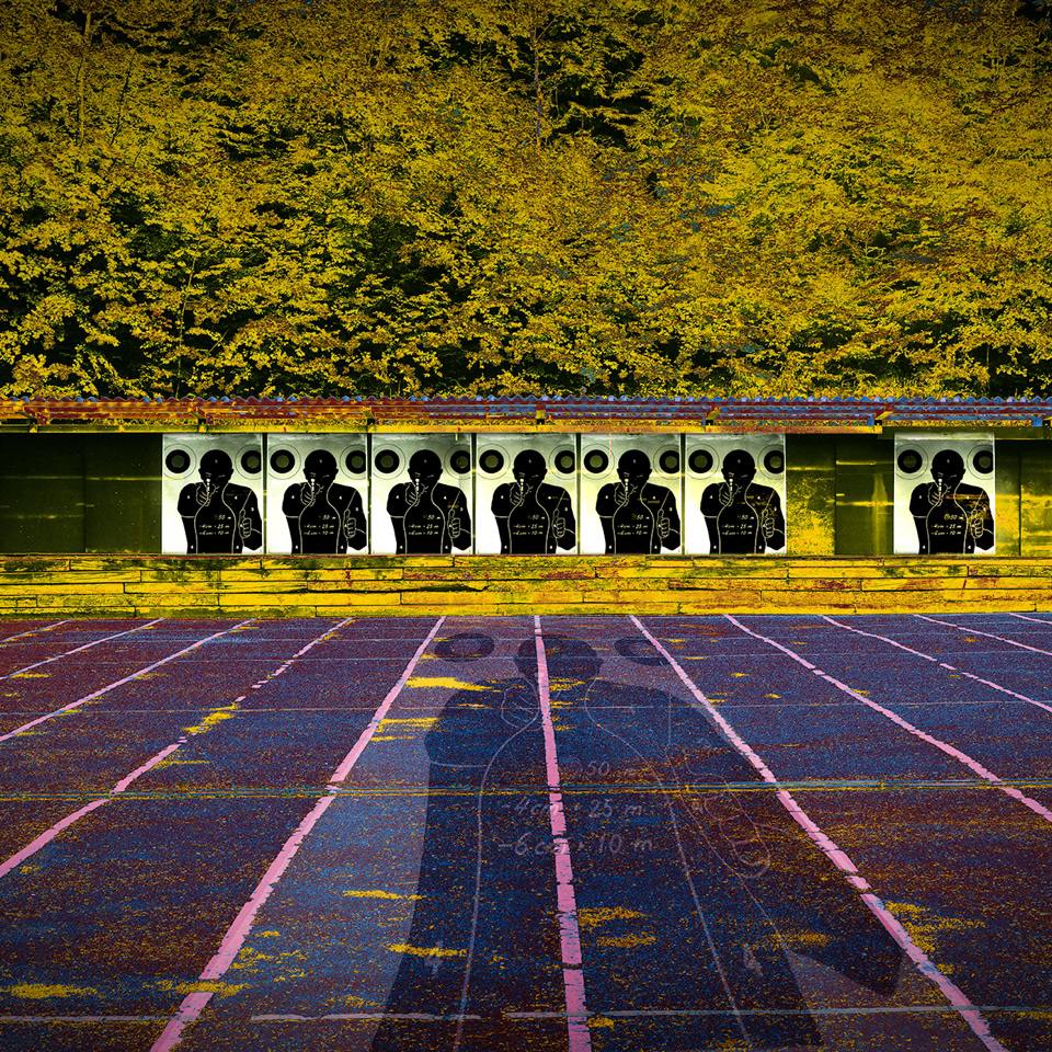 A running track with lanes in the foreground, a row of targets in the middle ground, and trees with yellow leaves in the background.