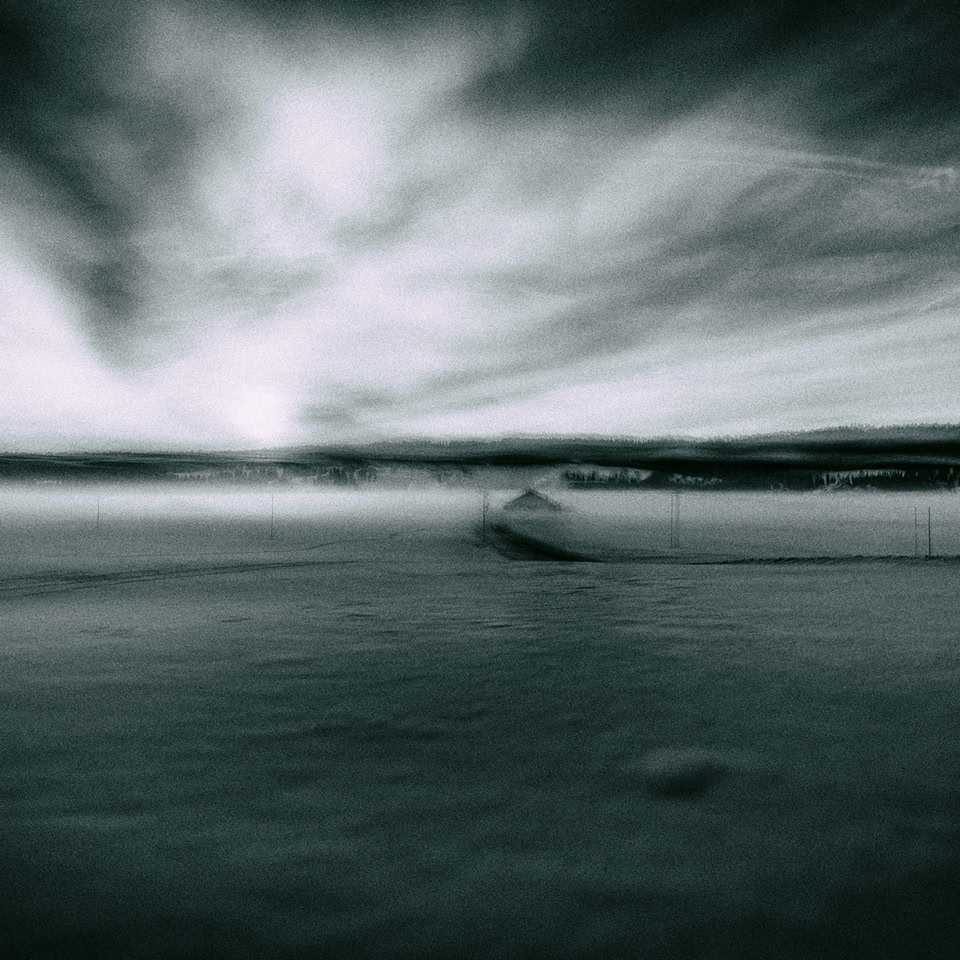 Paysage flou en noir et blanc avec un ciel nuageux et une étendue d'eau.