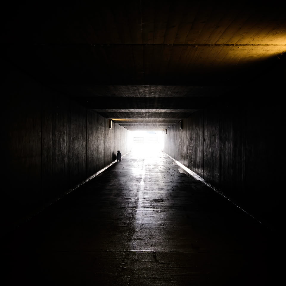 Un tunnel sombre avec une lumière vive au bout.